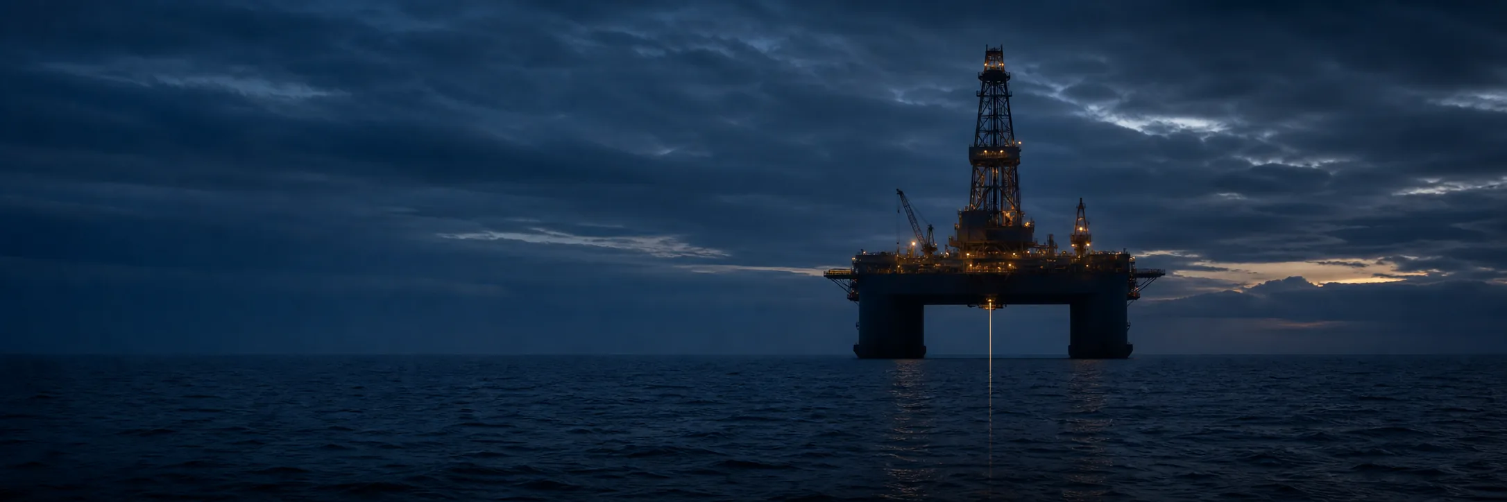 Un navire de forage flottant au crépuscule, avec le train de riser descendant verticalement du moonpool dans la mer